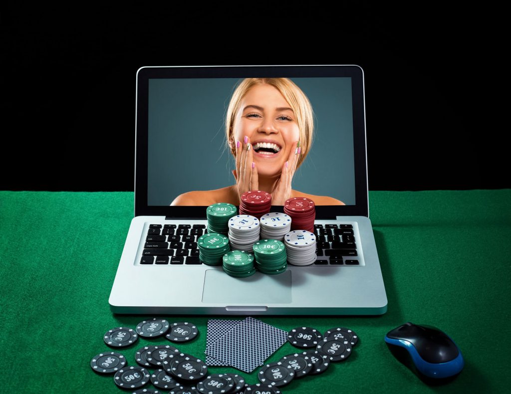 53162707 - green table with casino chips, cards on notebook, image of smiling woman on screen of laptop. concept for online gambling.